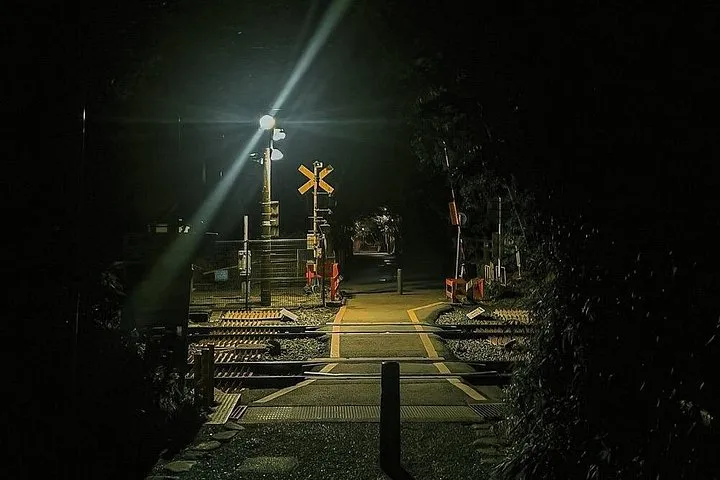 Railway crossing lit by a single lamp on the dark walk to the Arashiyama Bamboo Forest at night, Kyoto